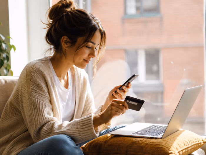 Woman sending a payment from her phone and laptop